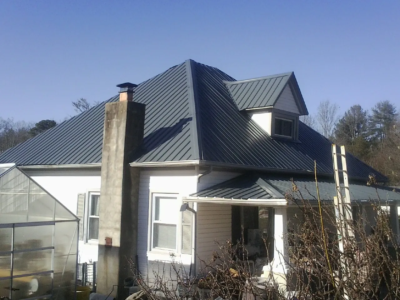 Dark blue standing seam metal roof on a white farmhouse with dormer — Slate & Tile Roof Repair by Roofing Brothers in Fort Recovery