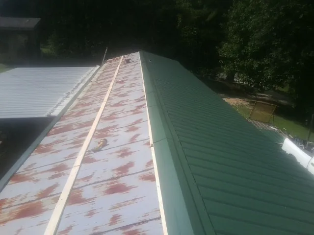 Old rusted panels beside newly installed green metal roofing — Wind Damage Roof Repair by Roofing Brothers in Fort Recovery