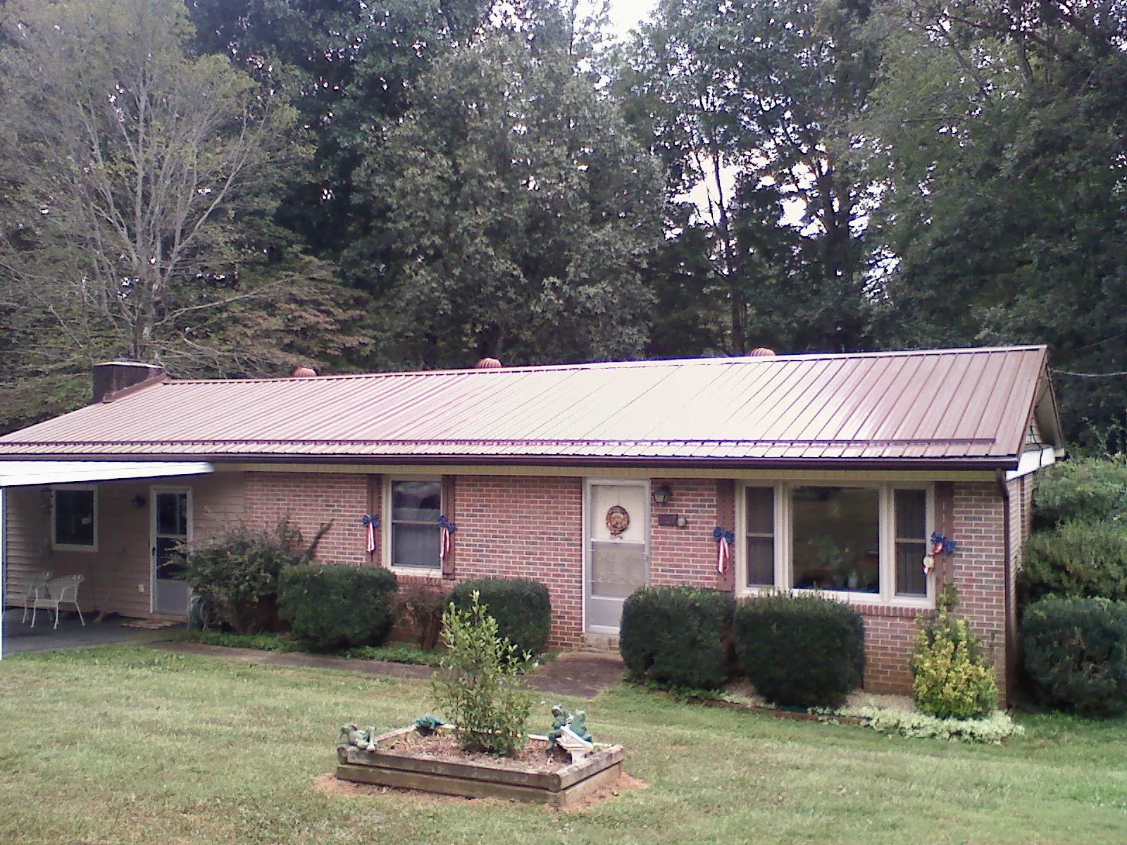 Bronze metal roof on a brick ranch home with a carport in Fort Recovery