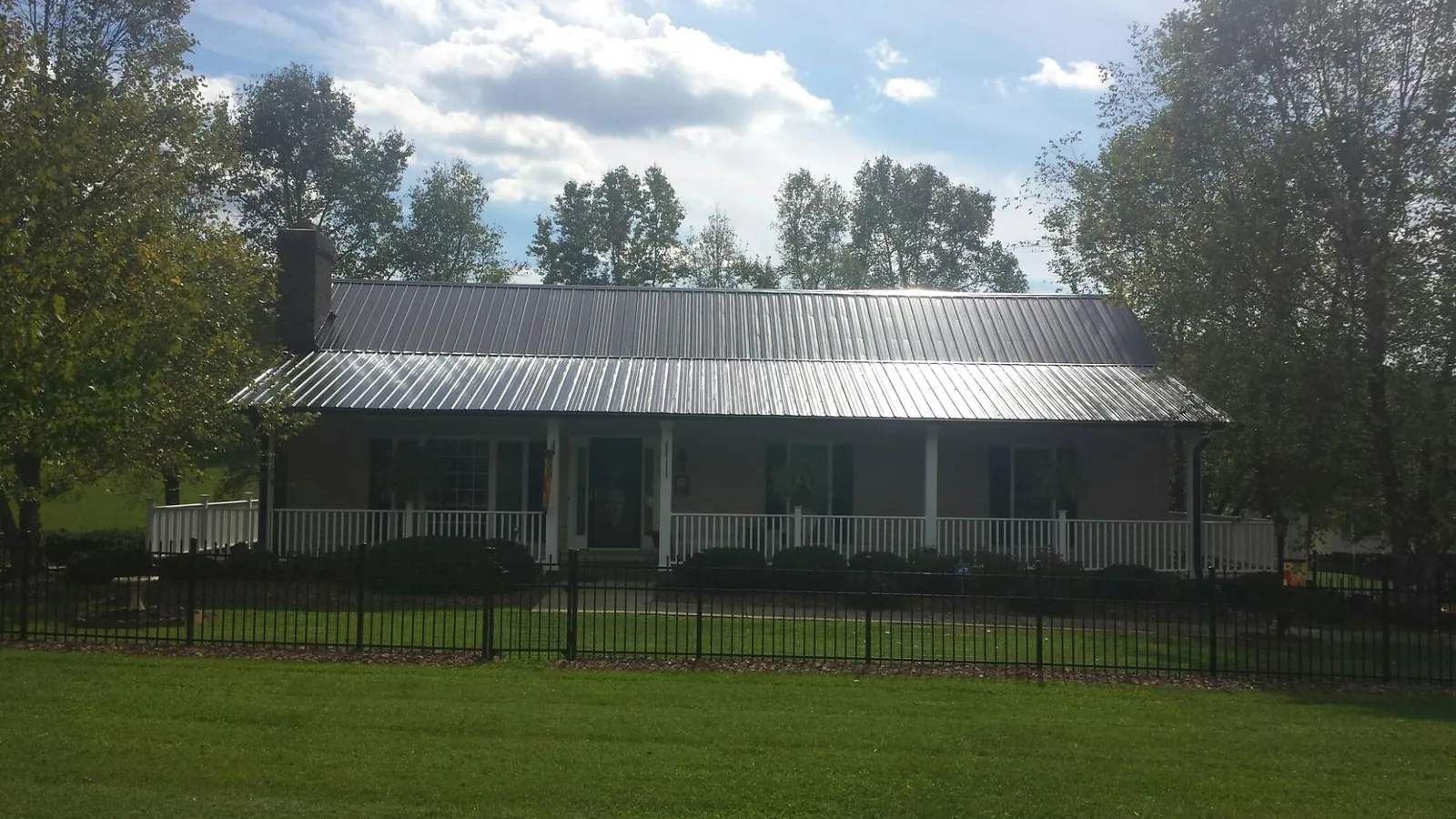 Gray metal roof on a brick ranch with a full width front porch — Gutter Guard Installation work by our crew in Fort Recovery