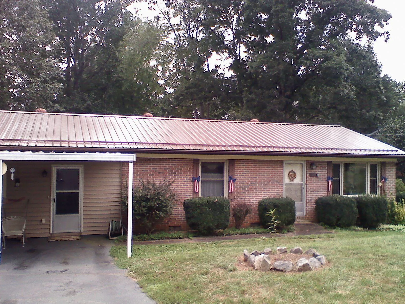 Bronze metal roof and carport on a brick ranch home — Roof Repair work by our crew in Fort Recovery