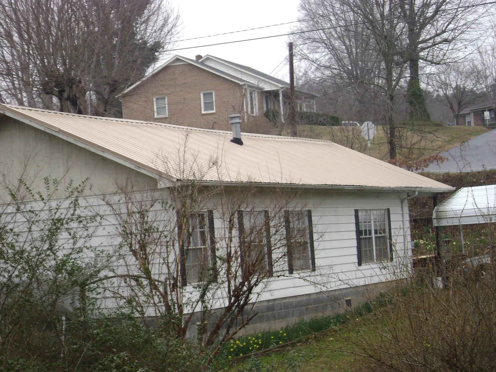 Tan metal roof on a white sided house set into a hillside — Commercial Roofing by Roofing Brothers in Fort Recovery