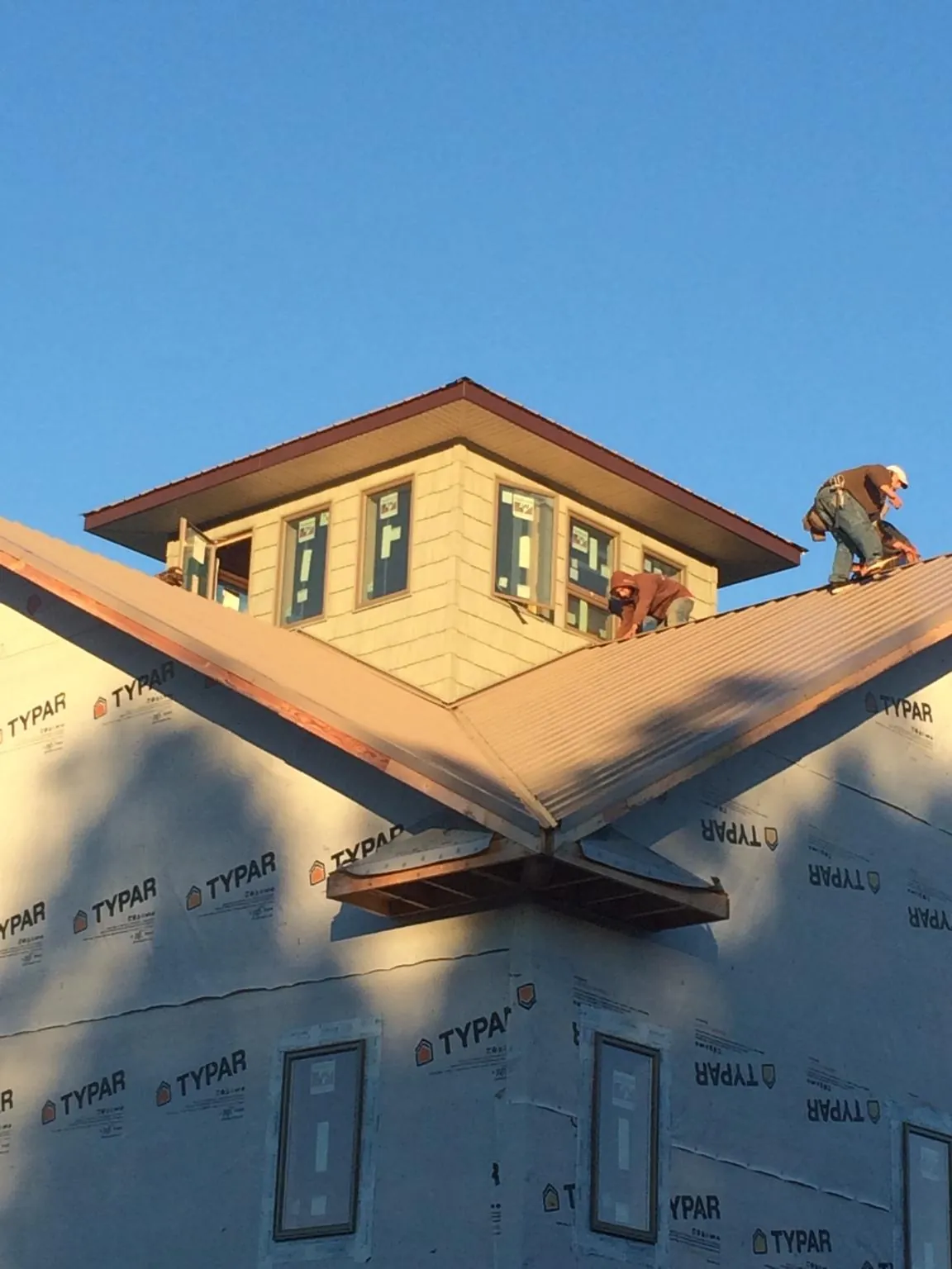 Roofers working around a rooftop cupola on a new metal roof at sunset — Roof Waterproofing in Fort Recovery by Roofing Brothers